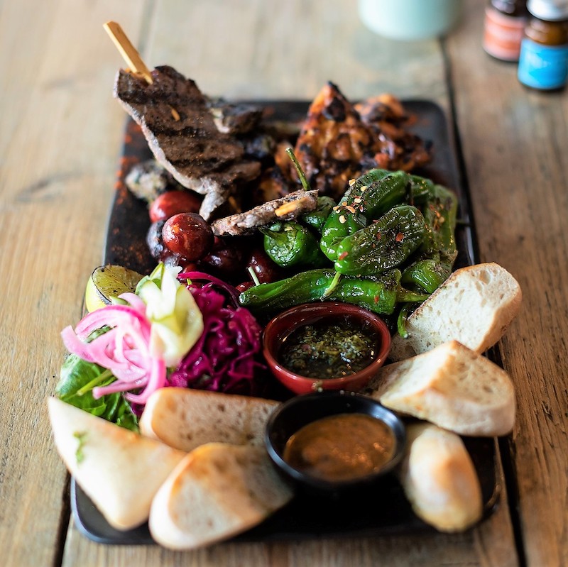 A loaded sharing platter of grilled meats and breads