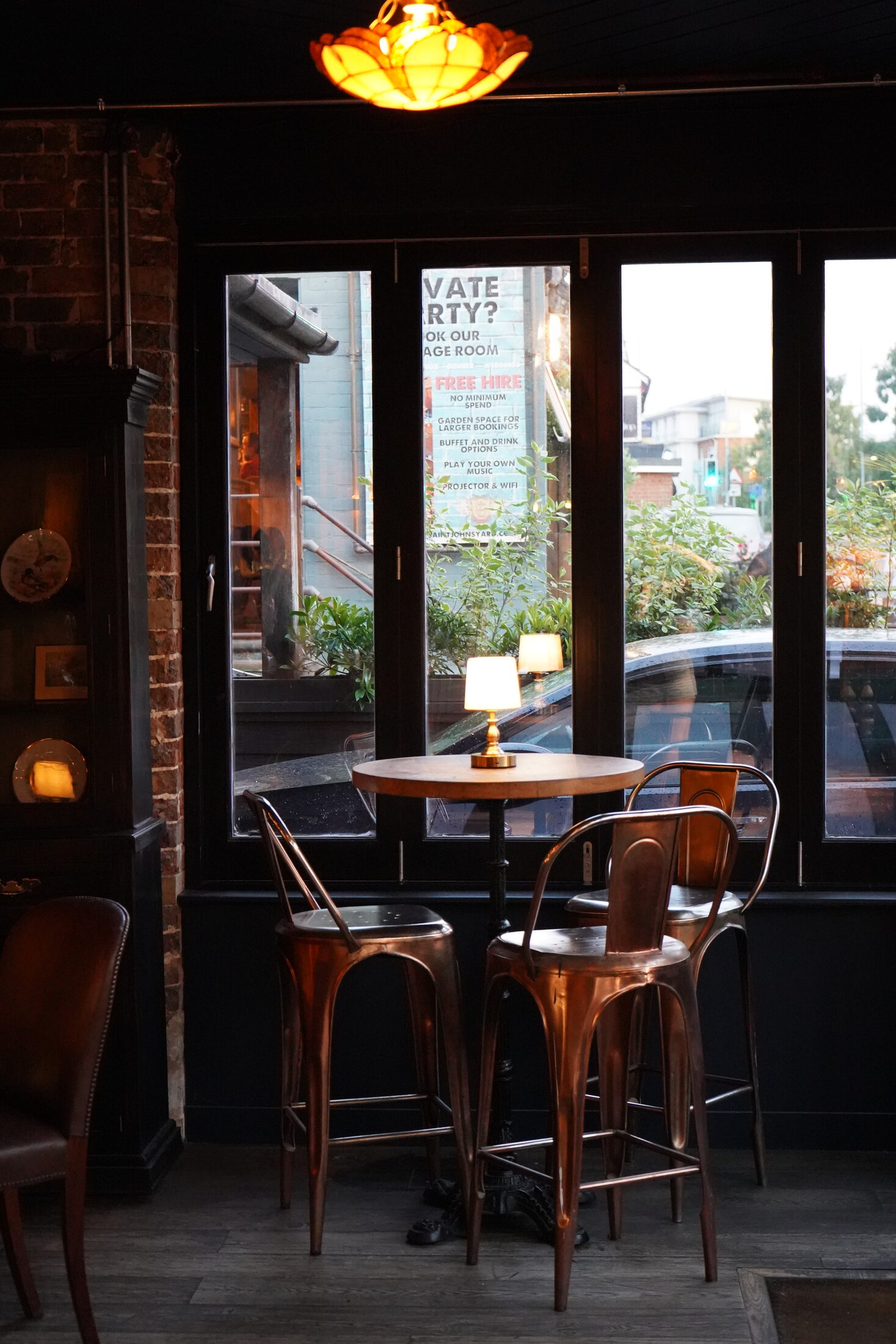 Window table with copper chairs and a small lamp