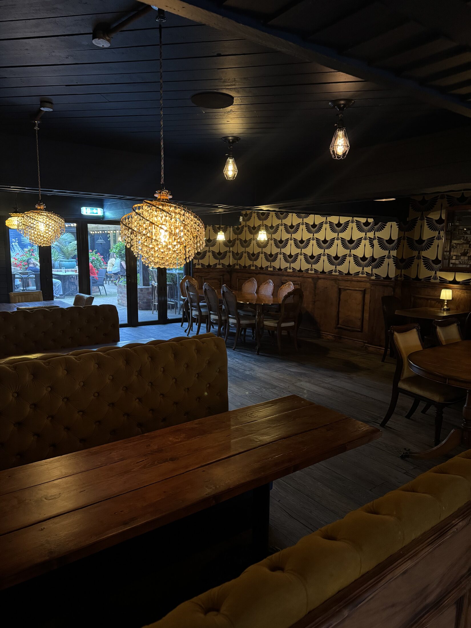 Lounge seating with chandeliers, patterned wallpaper and garden doors